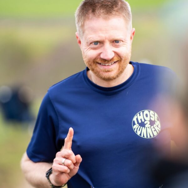 Chris holding up one finger to represent first place. He wears a Keep On Running t-shirt